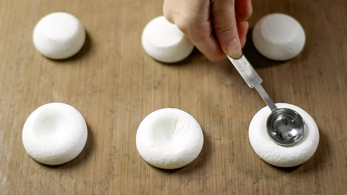 Place marshmallows on a baking sheet lined with parchment paper and bake in a preheated oven at 120°C (250°F) for 15 minutes.

Using the back of a lightweight spoon or similar tool, create a hollow in the center of the softened marshmallows. (The marshmallows are soft but still have some elasticity. Pressing with too much force can create a hole at the bottom, while pressing too lightly may not create a hollow. Apply gentle pressure several times.)
軽量スプーンの背などを使って、柔らかくなったマシュマロの中心にくぼみを作ります。（マシュマロは柔らかくなっていますが弾力があります。強い力で押すと底に穴があいてしまいますし、弱いとくぼみができません。軽い力で何度か押してください。）