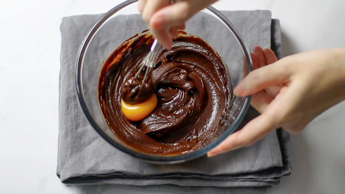 In a bowl, melt the chocolate using a double boiler or microwave.

Add one egg yolk at a time to the melted chocolate and mix. (Be careful not to add the egg yolks to the chocolate while it is too hot, as it may cook the yolks and form lumps. Test the temperature of the bowl with your hand; if it's too hot, let it cool for about 5 minutes.)