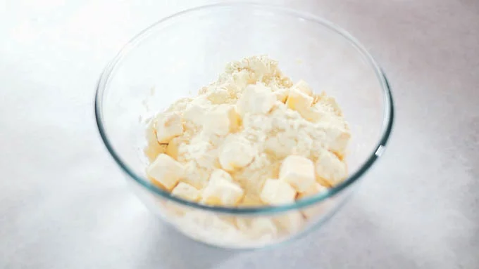 バターを2cm角に切ります。冷水に塩を加えて溶かしておきます。
薄力粉と強力粉をふるい入れたボールにバターを入れ、バターに粉をまぶすような感じでさっと混ぜます。 ＊ここではバターのかたちを保ったままで、練ったりこねたりバターを潰したりしないようにしてください！