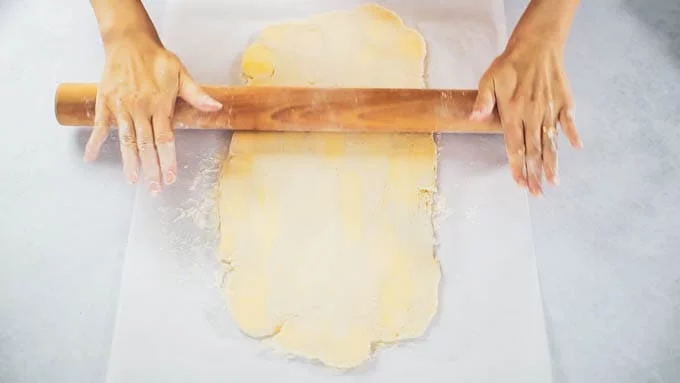 打ち粉をした台に生地を取り出して、バター生地を3倍の長さの長方形に伸ばします（約 18x45cm）。向こう側から手前に⅓折り込み、手前からまた⅓折り込みます。（三つ折り1回目）