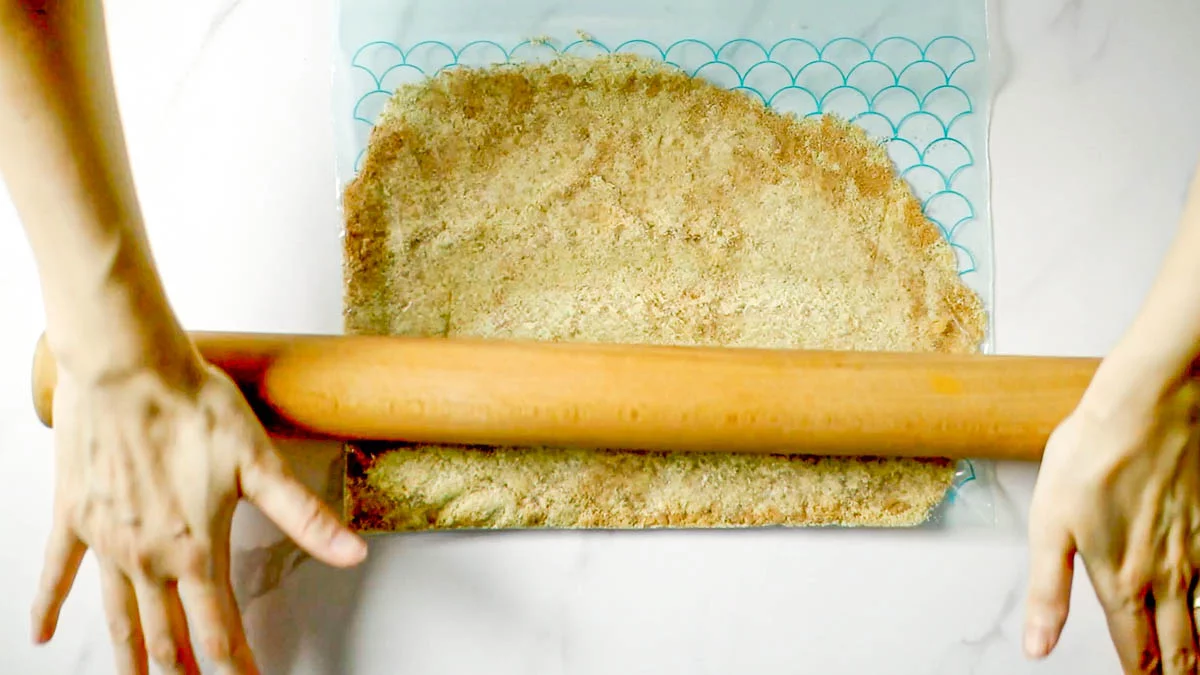Put the cookies in a zipper bag, beat them with a rolling pin to break them into small pieces, pour in the melted butter, and rub in to blend well.