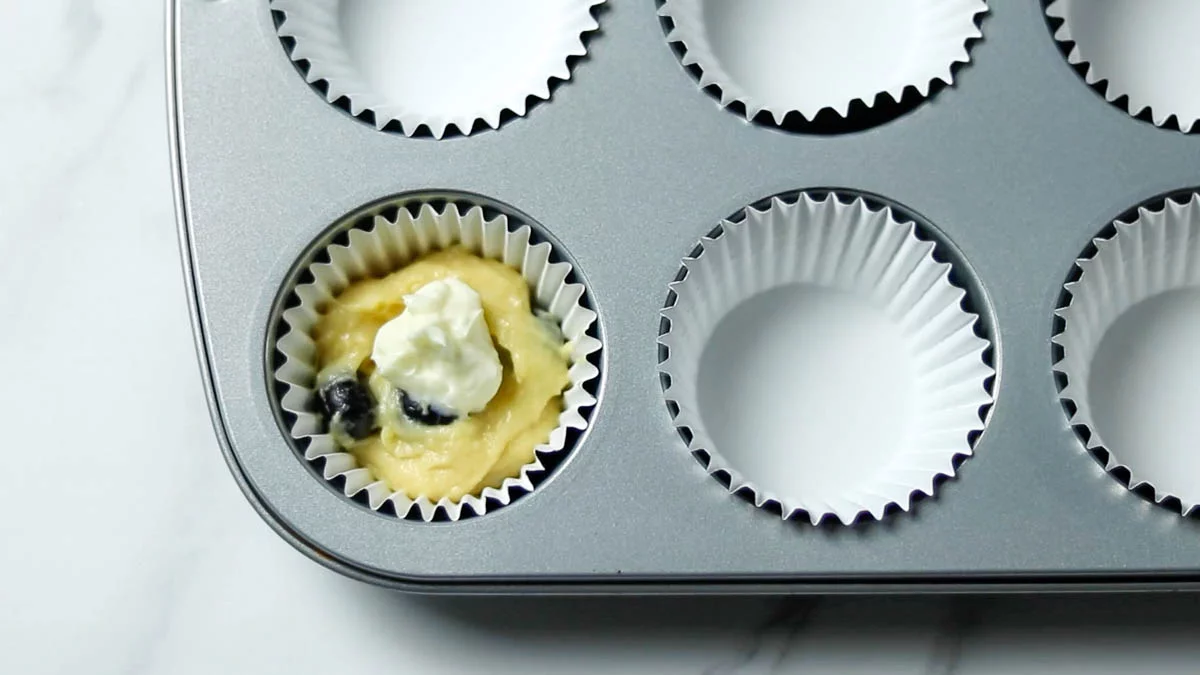 Fill the muffin cups lined with parchment paper with the batter, filling them about halfway. Place the cheesecake filling in the center.