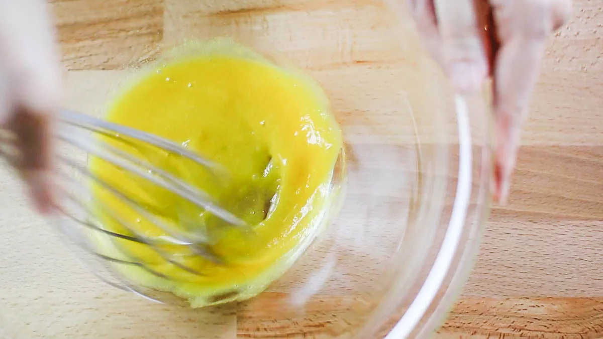 卵黄の入ったボウルに半量のグラニュー糖（大さじ1）とはちみつを加え、ホイッパーでよく混ぜます。