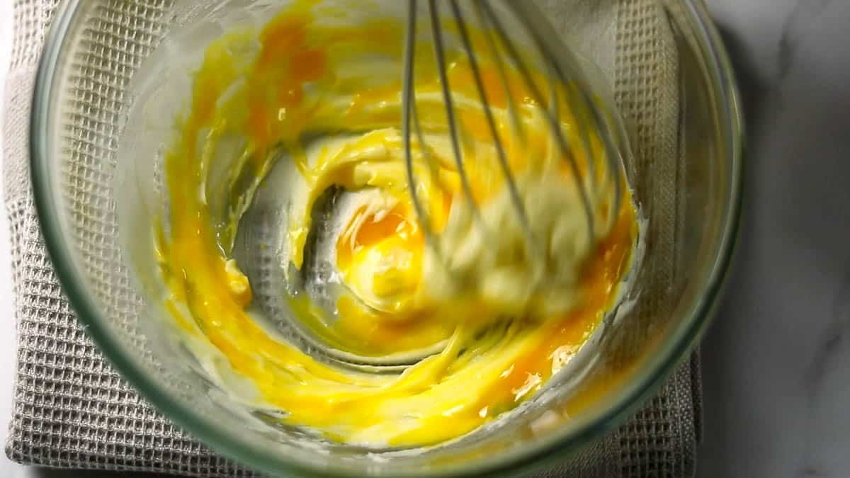 卵黄と水を合わせたものを加え、よく混ぜ合わせます。最初分離したような感じになりますが、混ぜ続けるときれいに乳化した生地になります。