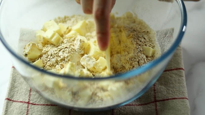 角切りにした冷えたバターを加えてスケッパーなどを使ってバターを切り刻みながら混ぜ合わせます。生地がそぼろ状になるまで混ぜます。
