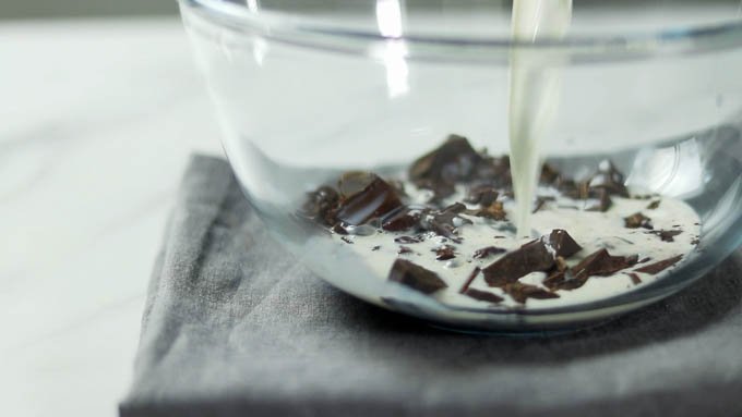チョコレートを刻んでボウルに入れます。
牛乳を沸騰直前まで温めます。チョコレートに注ぎ入れ、溶けるまで少し置いてから混ぜ合わせます。