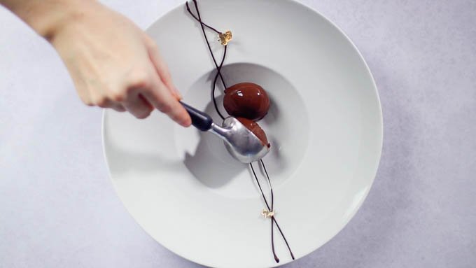 冷やしたお皿にチョコレートで2本線を描き、金箔を飾ってからチョコレートアイスクリームをのせます。