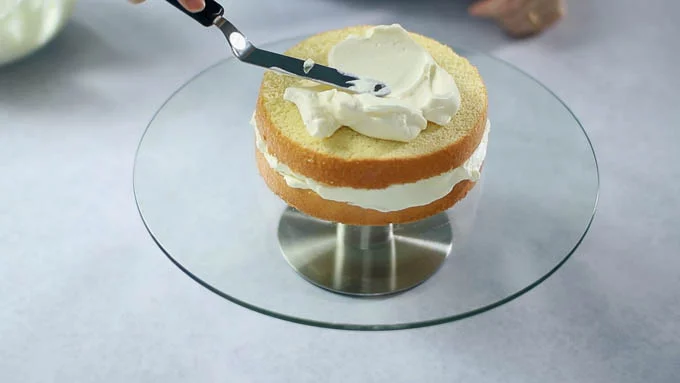 回転台に1枚目のスポンジケーキを置いて必要な量のクリームをパレットナイフで塗り広げます。