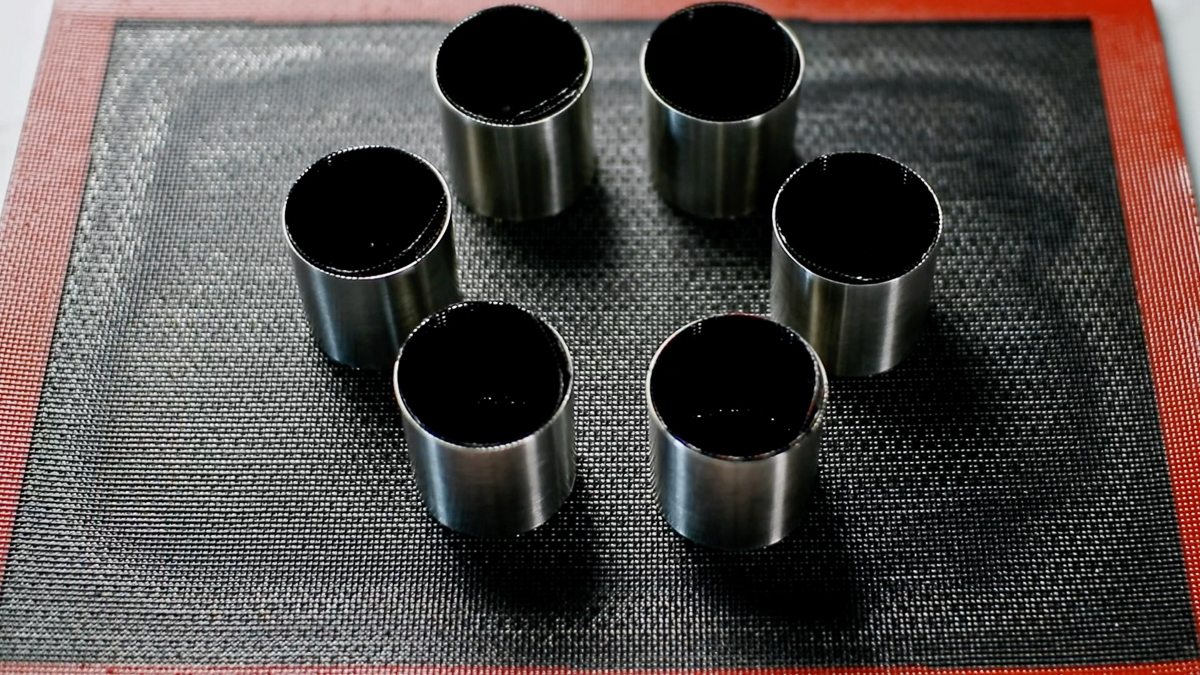 穴あき天板にシリコンマットを敷き、タルトリングを並べ、各リングの中にカットしたマットを敷き込みます。