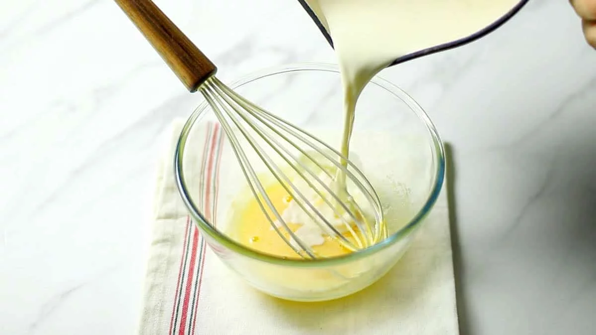 鍋に牛乳と生クリームを入れて温め、卵黄とグラニュー糖に半量を注ぎ入れ混ぜ合わせます。
