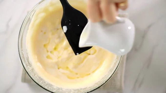 牛乳と溶かしたバターをゴムベラに伝わせながら生地全体に回し入れ、手早く混ぜ合わせます。