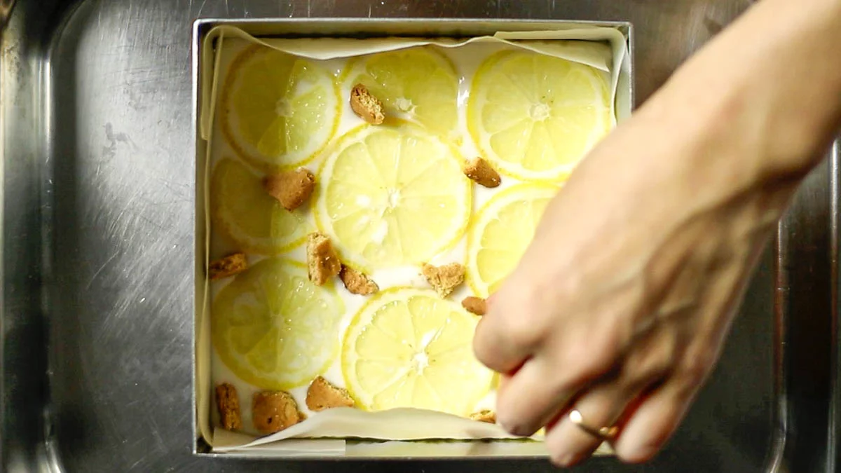 Place lemon slices and crushed biscuits on top, then place the container in the freezer for about 2 hours to firm up and set.