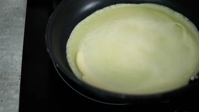 フライパンを熱して、キッチンペーパーに油を染み込ませて油を敷きます。
レードルの7-8分くらいまで生地を入れてフライパンに注ぎ入れ、すぐにフライパンを回して均等に薄く広げます。
常に同じ量の生地で焼けるようにレードルで量を調節してください。