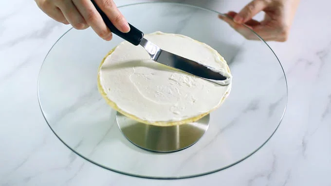 ケーキの回転台にクレープをのせて、少量のクリームを塗り広げます。