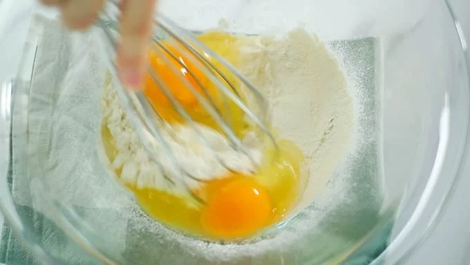 ボウルに薄力粉、グラニュー糖、塩をふるい入れます。卵を加え、ホイッパーでよく混ぜ合わせます。