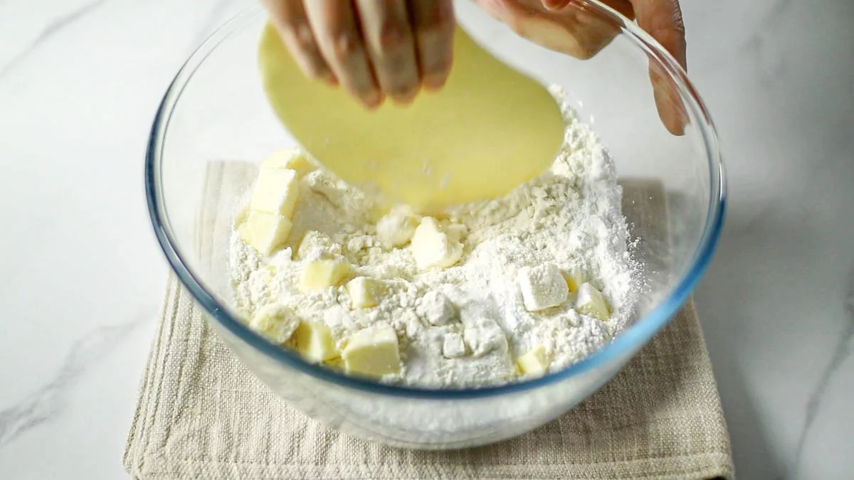 ボウルに薄力粉とベーキングパウダー、塩、グラニュー糖、冷たい角切りにしたバターを入れます。カードでバターを刻みながら混ぜ合わせます。粉チーズ状になるくらいまでさらさらな状態になればOKです。