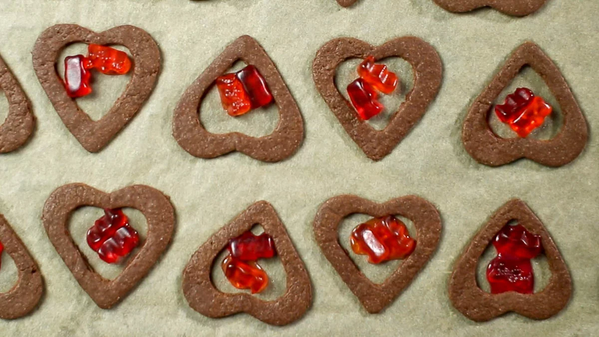 Once the cookies are done baking, remove them from the oven and immediately place two gummy candies inside each heart-shaped hollow. (*The residual heat from the baking sheet will melt the gummy candies, but if they don't melt completely, you can place them inside the turned-off oven to melt with the residual heat.)