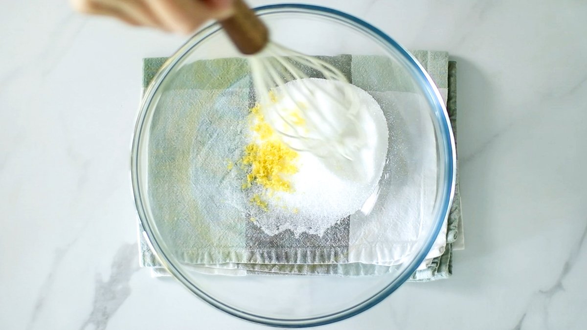 ボウルにグラニュー糖とレモンの皮のすりおろしを入れて混ぜ合わせます。