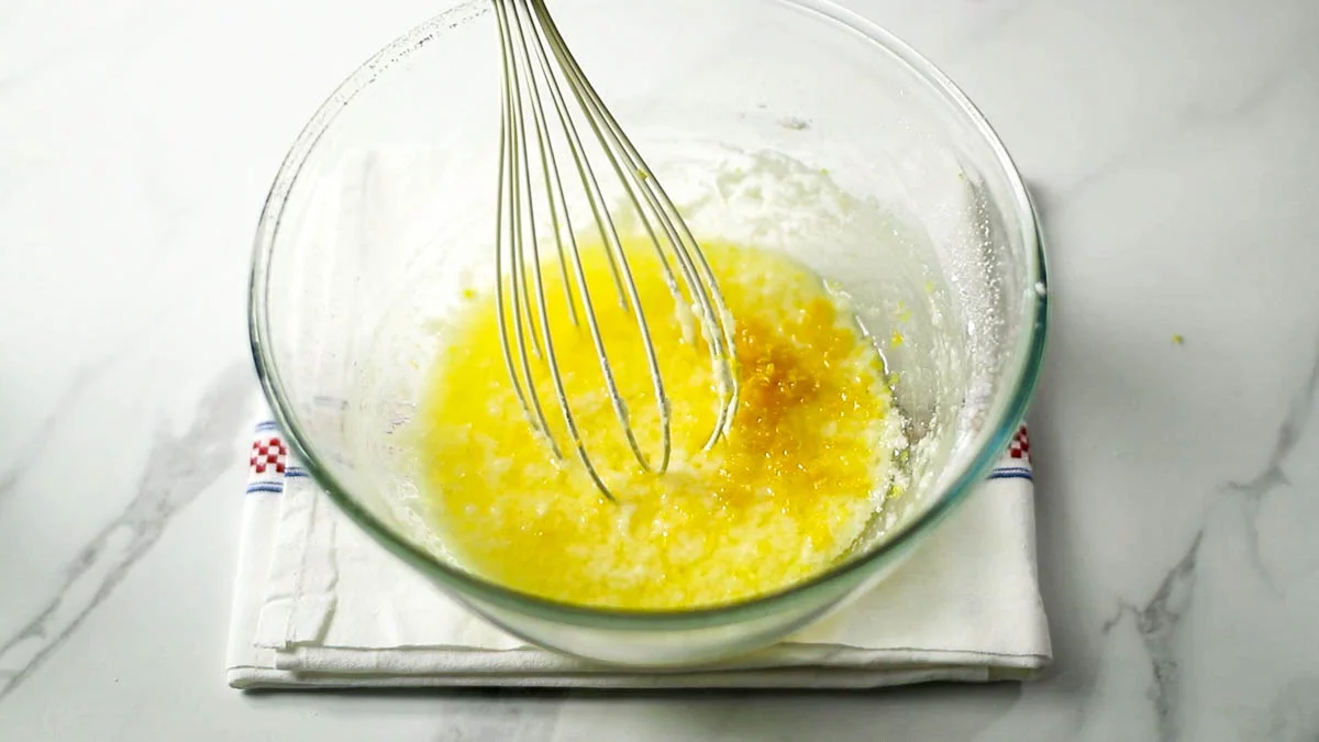 バターをレンジで溶かし、粉砂糖を加えてホイッパーで混ぜます。分離したような状態になりますが、そのままで大丈夫です。レモンの皮とレモン汁を加えます。