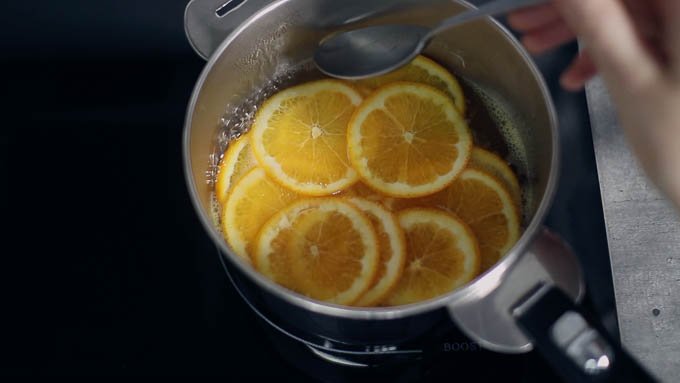 鍋にグラニュー糖と水を入れて中火にかけて、グラニュー糖が全部溶けたらオレンジを加えます。アクを取りながら、弱火で5分ほど煮ます。
粗熱が取れたら菜箸などでオレンジのスライスを取り出し、キッチンペーパーの上に重ならないように並べて水気を切ります。