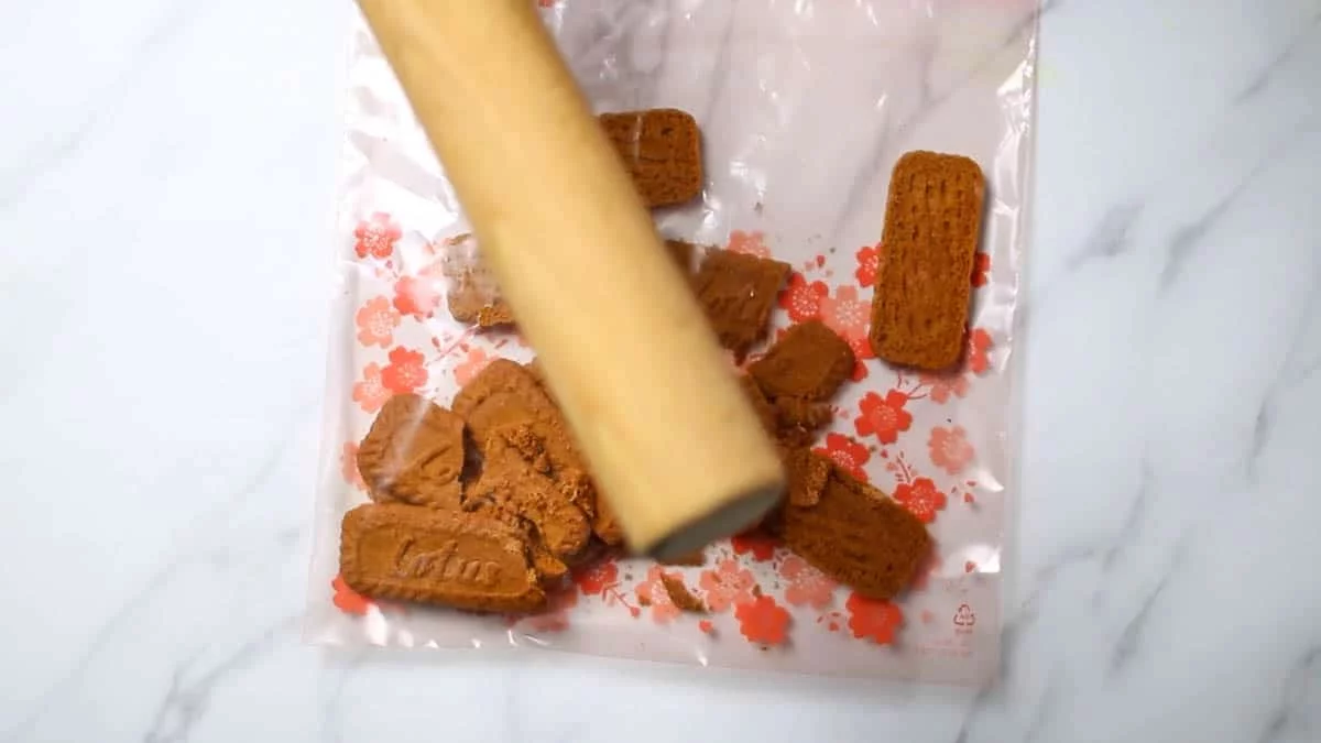 Put the speculoos in a zipper bag, beat them with a rolling pin to break them into small pieces, pour in the melted butter, and rub them together to blend them well