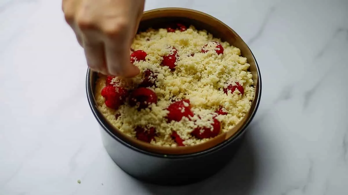 Sprinkle crumble over the cheesecake batter and place raspberries on top of it Sprinkle more crumble on top of that, place raspberries, and sprinkle crumble on top of that