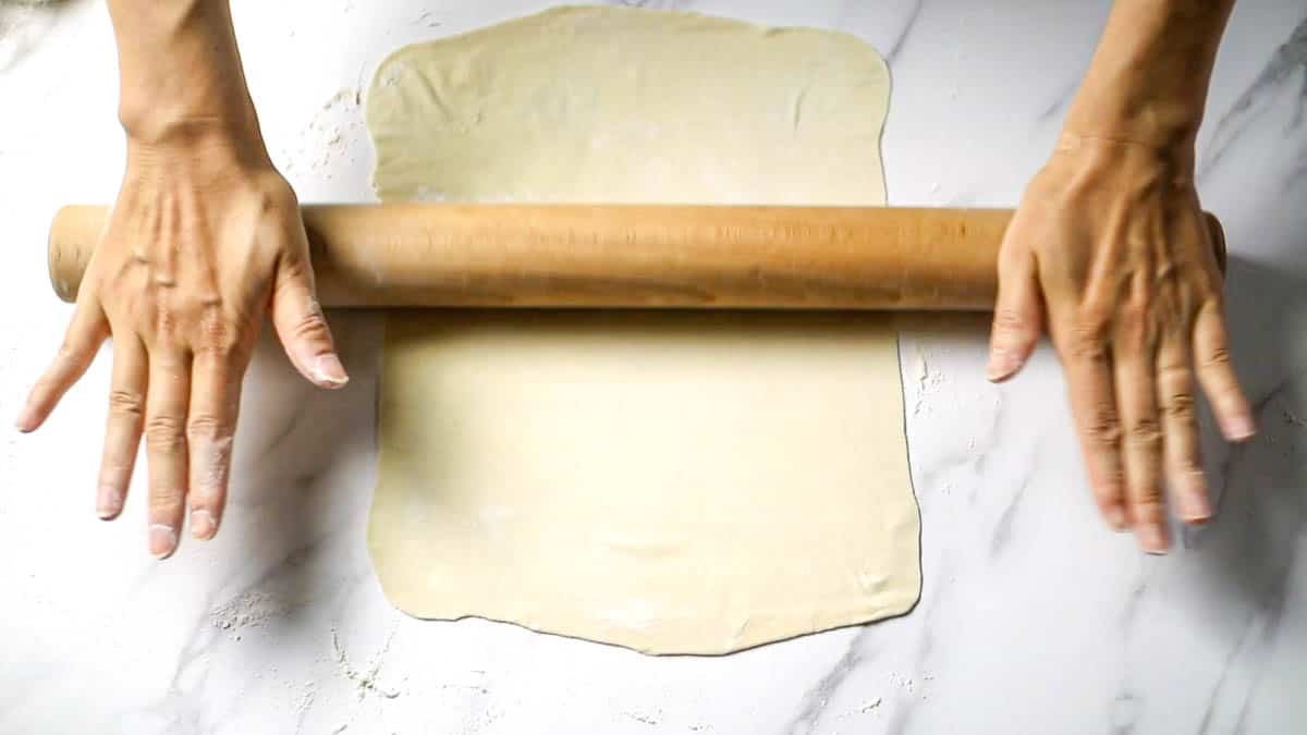 Place one of the 6 equal portions of dough on a floured board, roll it out lightly with your hands, and roll it out with a rolling pin into a rectangle about 35 cm (length) x 25 cm (width) Roll out the dough as thin as paper so that you can see your hands through it