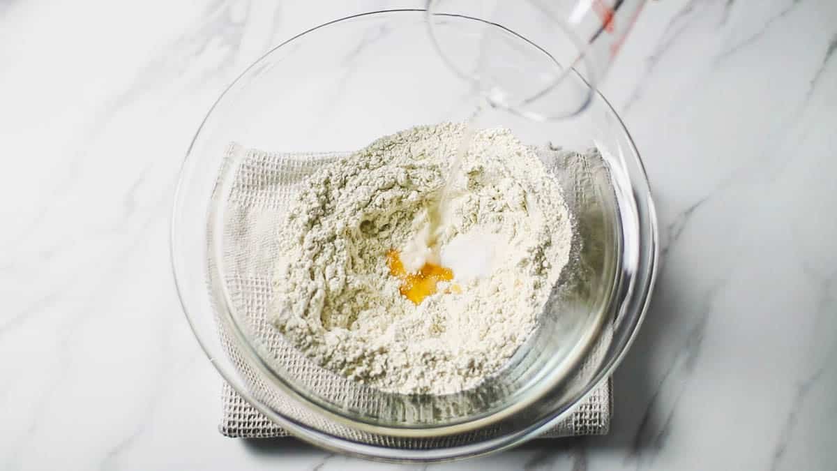 ボウルに強力粉、塩、はちみつを入れます。ボウルの中央にくぼみを作り、水を少しづつ注ぎ入れ混ぜ合わせます。