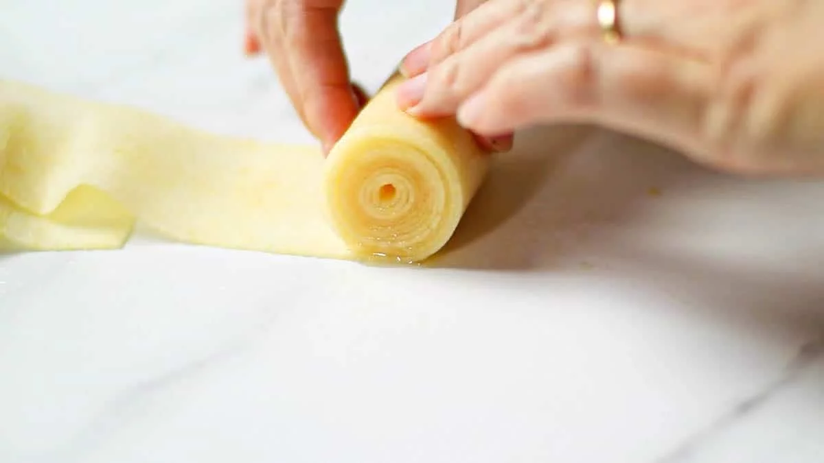 Roll the apple sheet tightly and firmly to make the center Then, connect the sheets of apples to form a large spiral