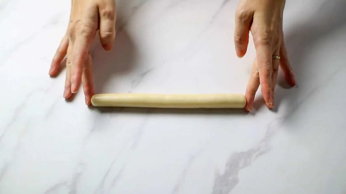 Divide the marzipan into two pieces and roll out each piece into a stick about 20 cm long