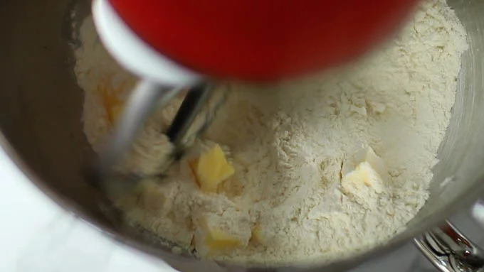 冷水に塩を入れて溶かしておきます。
スタンドミキサーに強力粉と薄力粉、サイコロ状に切ったバターを加えて混ぜ合わせます。

