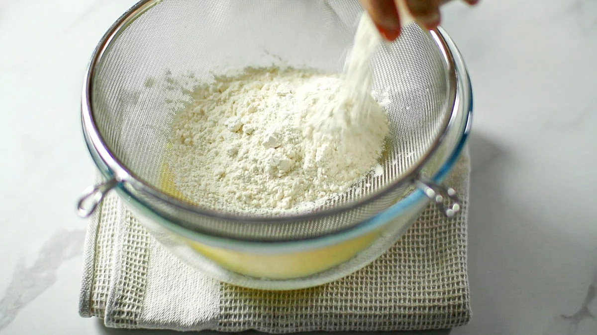Sift in 1 ½ cups of flour into the container of yogurt and 1 teaspoon of baking powder